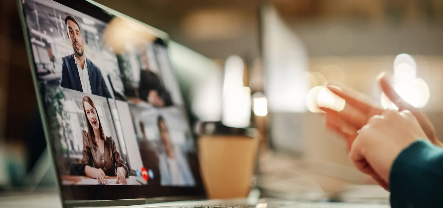 Person on a video call with several colleagues shown on a laptop screen